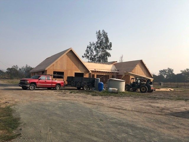 A red truck is parked in front of a house under construction.
