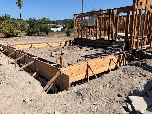 A house is being built in the middle of a dirt field.