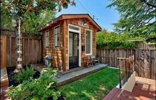 A small wooden shed in the backyard of a house.