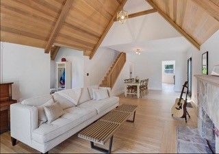 A living room with a couch , coffee table , fireplace and stairs.