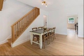 A dining room with a table and chairs and stairs leading up to the second floor.