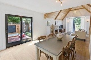 A living room with a dining table and chairs and sliding glass doors.