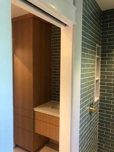 A bathroom with green brick walls and a sink.