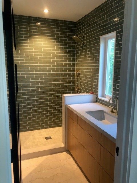 A bathroom with green brick walls and a sink