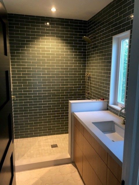 A bathroom with green brick walls and a sink