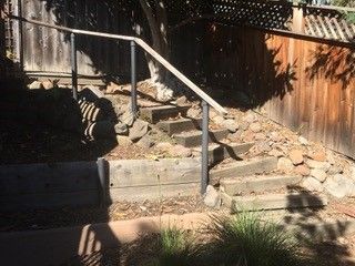 A set of stairs leading up to a wooden fence with a metal railing.