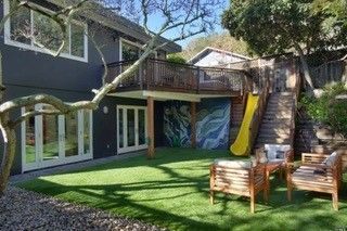 A house with a slide and stairs in the backyard.