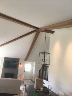 A living room with a dining table and a ceiling with wooden beams.