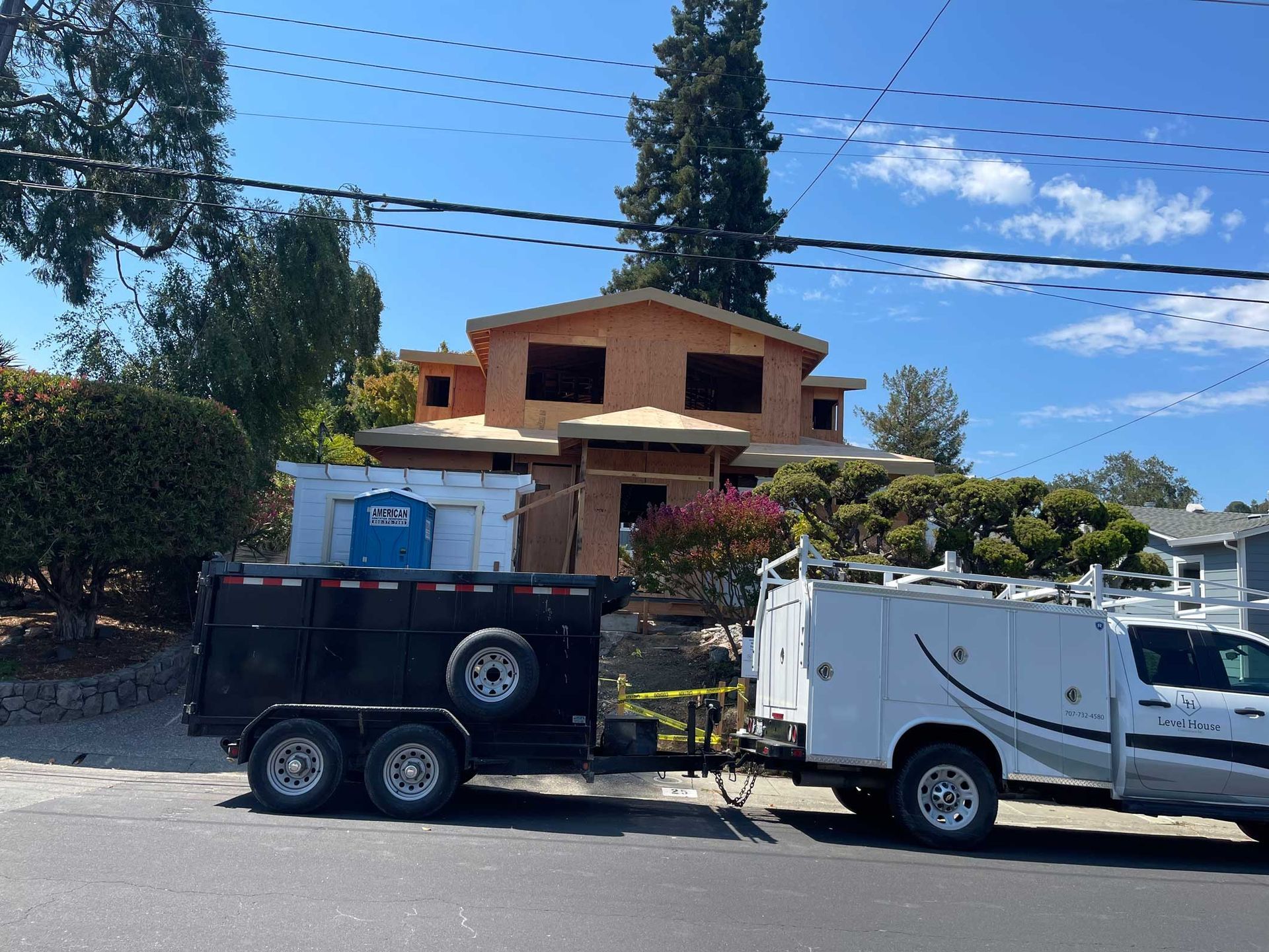 A white truck with a utility box on the back is parked in front of a house under construction