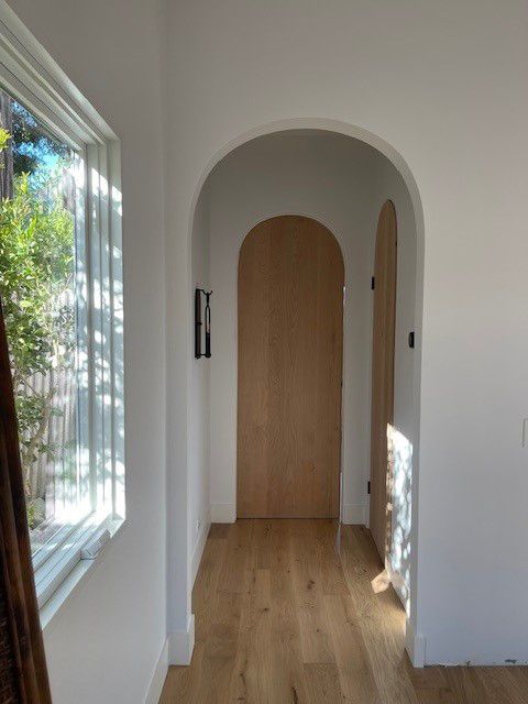 A hallway with a wooden door and a window
