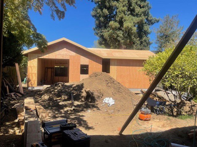 A house under construction with a pile of dirt in front of it.