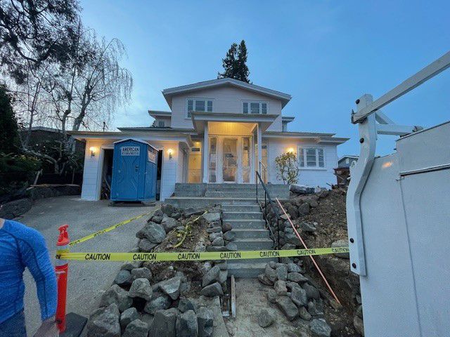 A large white house with a blue portable toilet in front of it