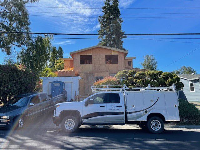 A white truck is parked in front of a house under construction.