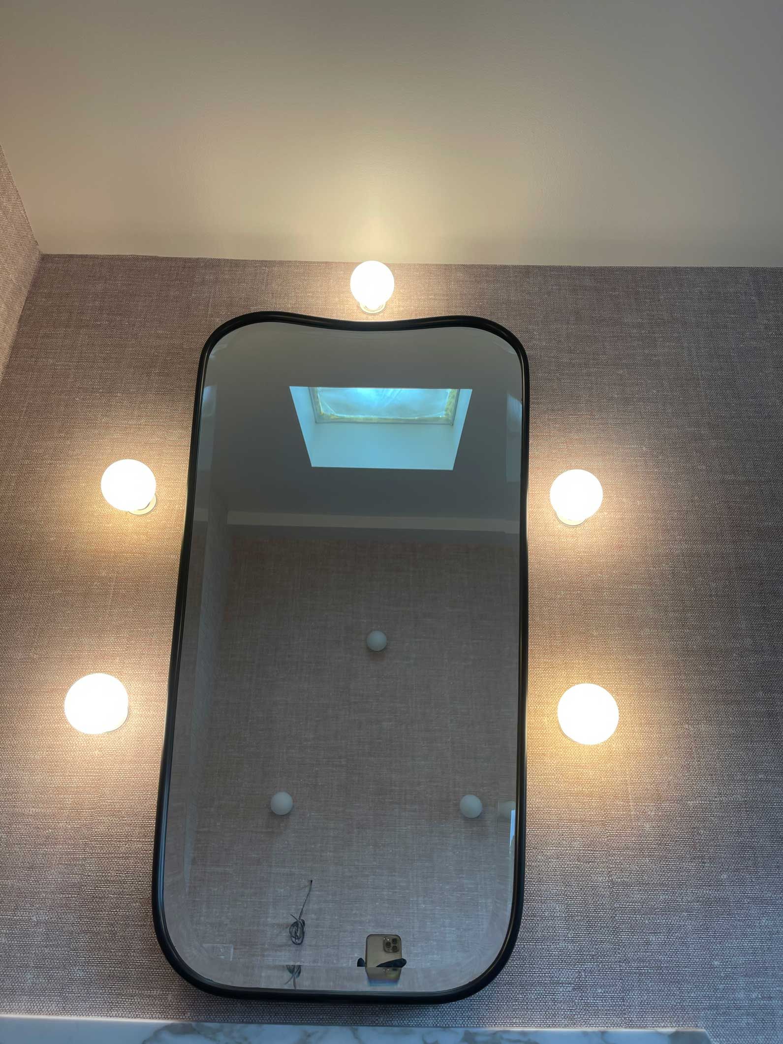 A mirror is hanging on a wall next to a skylight.