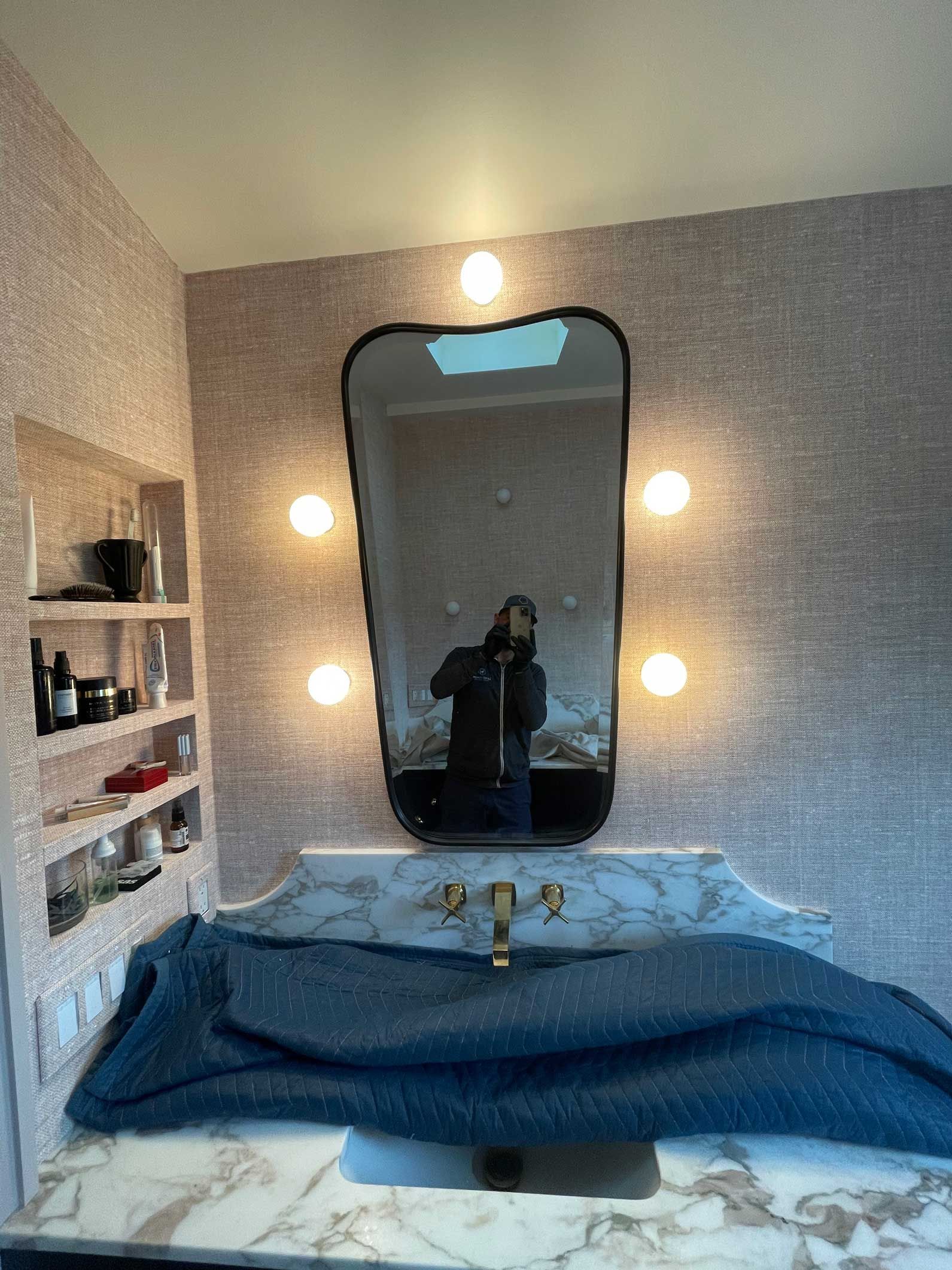 A bathroom with a sink and a mirror with lights on it.