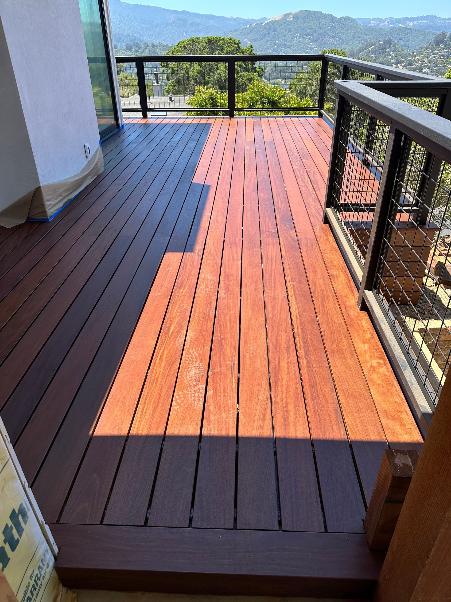 A wooden deck with a sandbox and a chalkboard in the backyard.