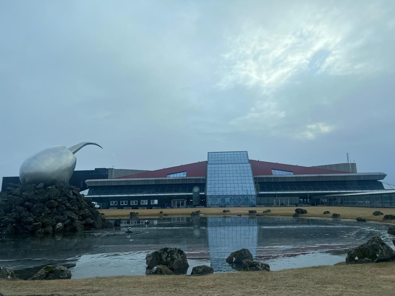 Exterior view of Keflavik International Airport terminal building in Iceland under a blue sky.