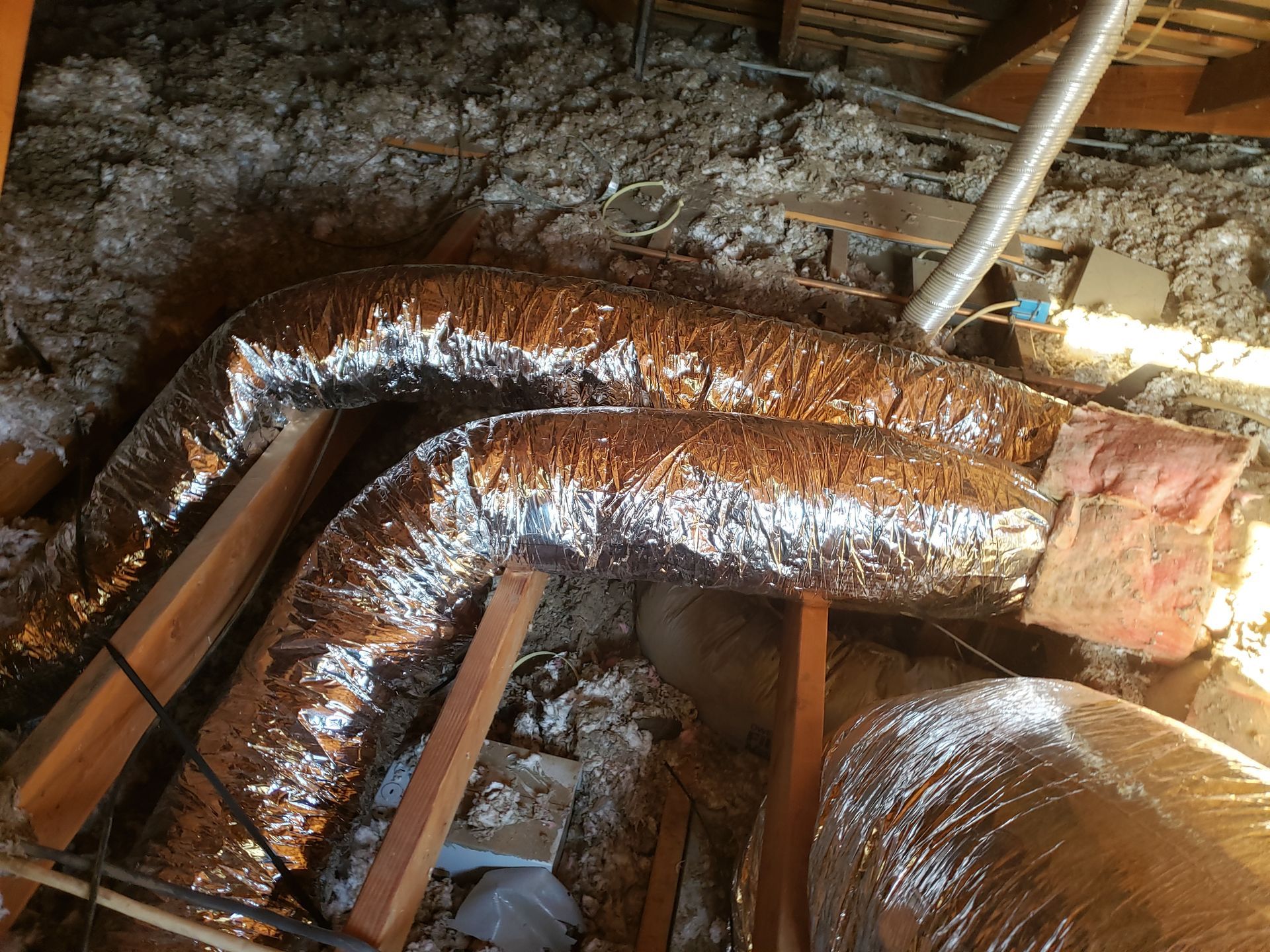 a bunch of ducts are sitting in the attic .