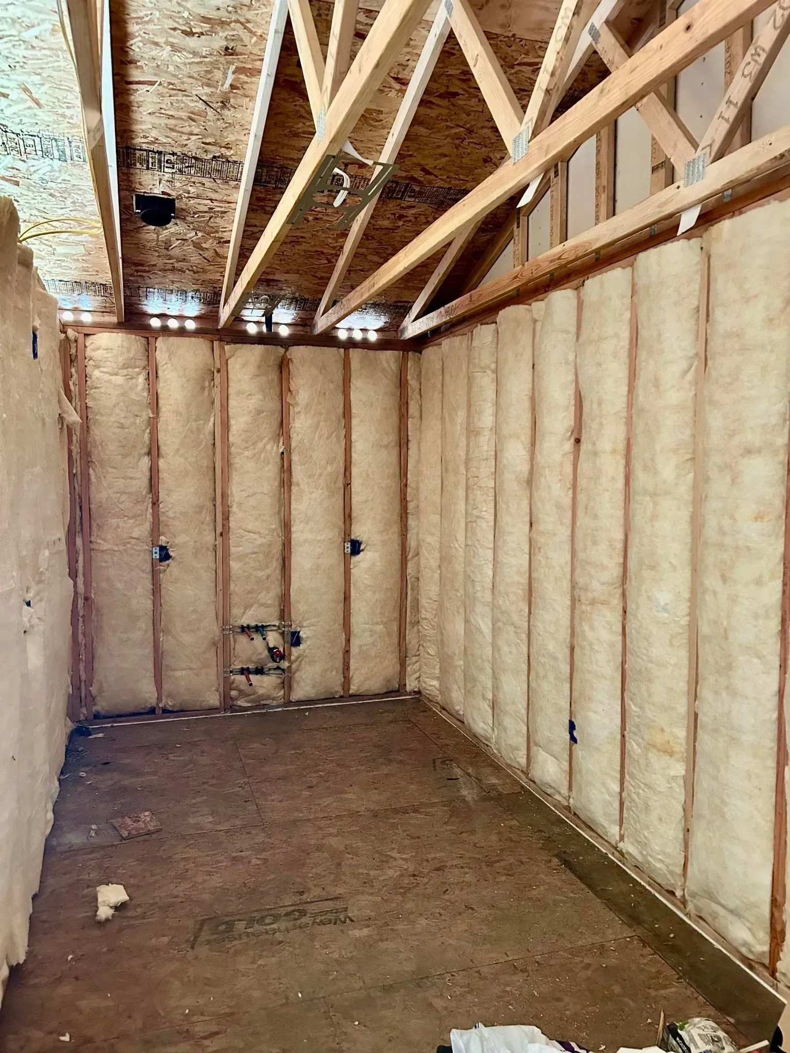 Interior of a room with spray foam insulation on walls and ceiling, exposed wooden beams.