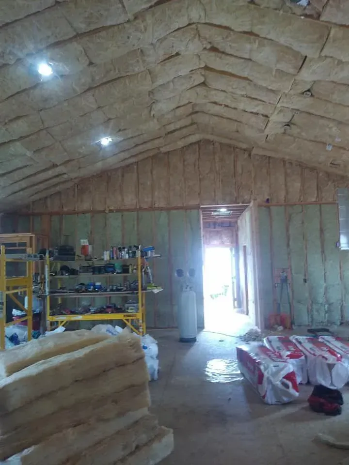 Interior view of a building under construction, with insulation on the walls and ceiling.