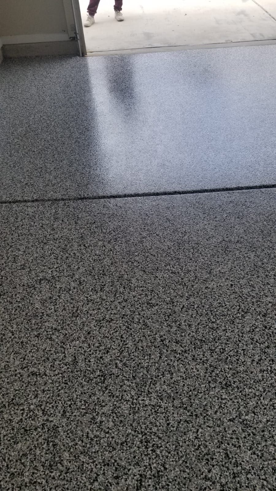 A close up of a gray floor with a person walking in the background.