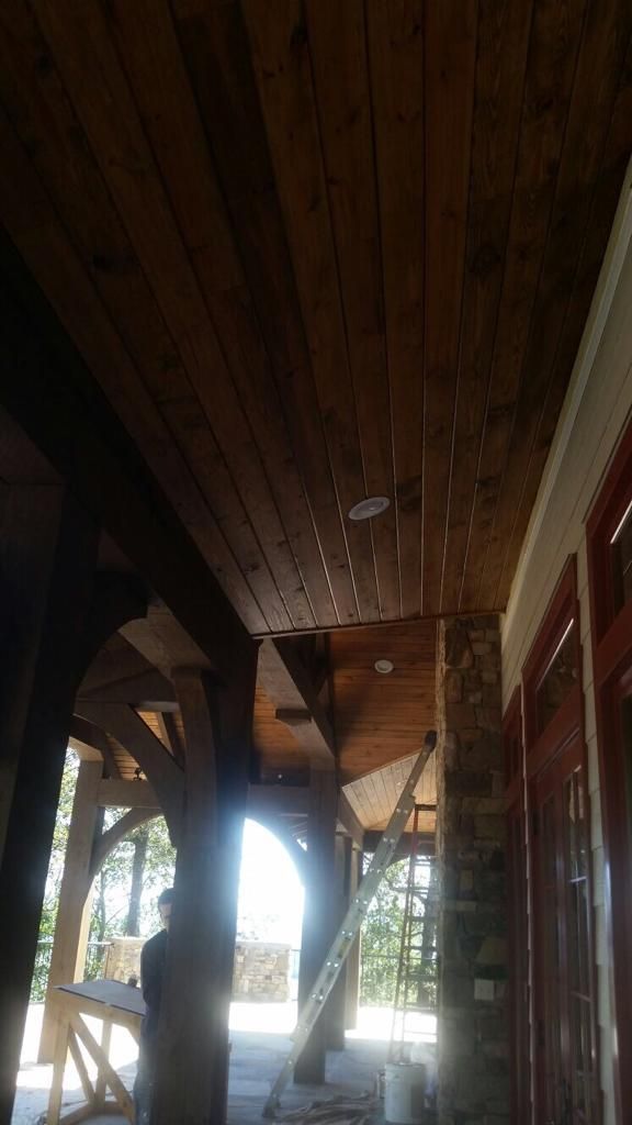 A man is standing in a room with a wooden ceiling.