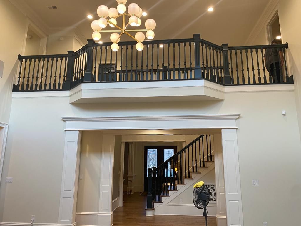 A large room with a balcony and stairs and a chandelier hanging from the ceiling.