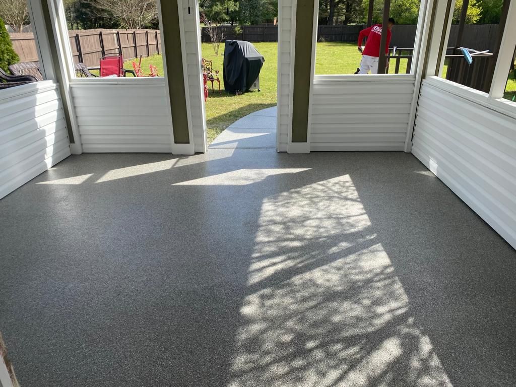 A man in a red shirt is standing in a room with a concrete floor.