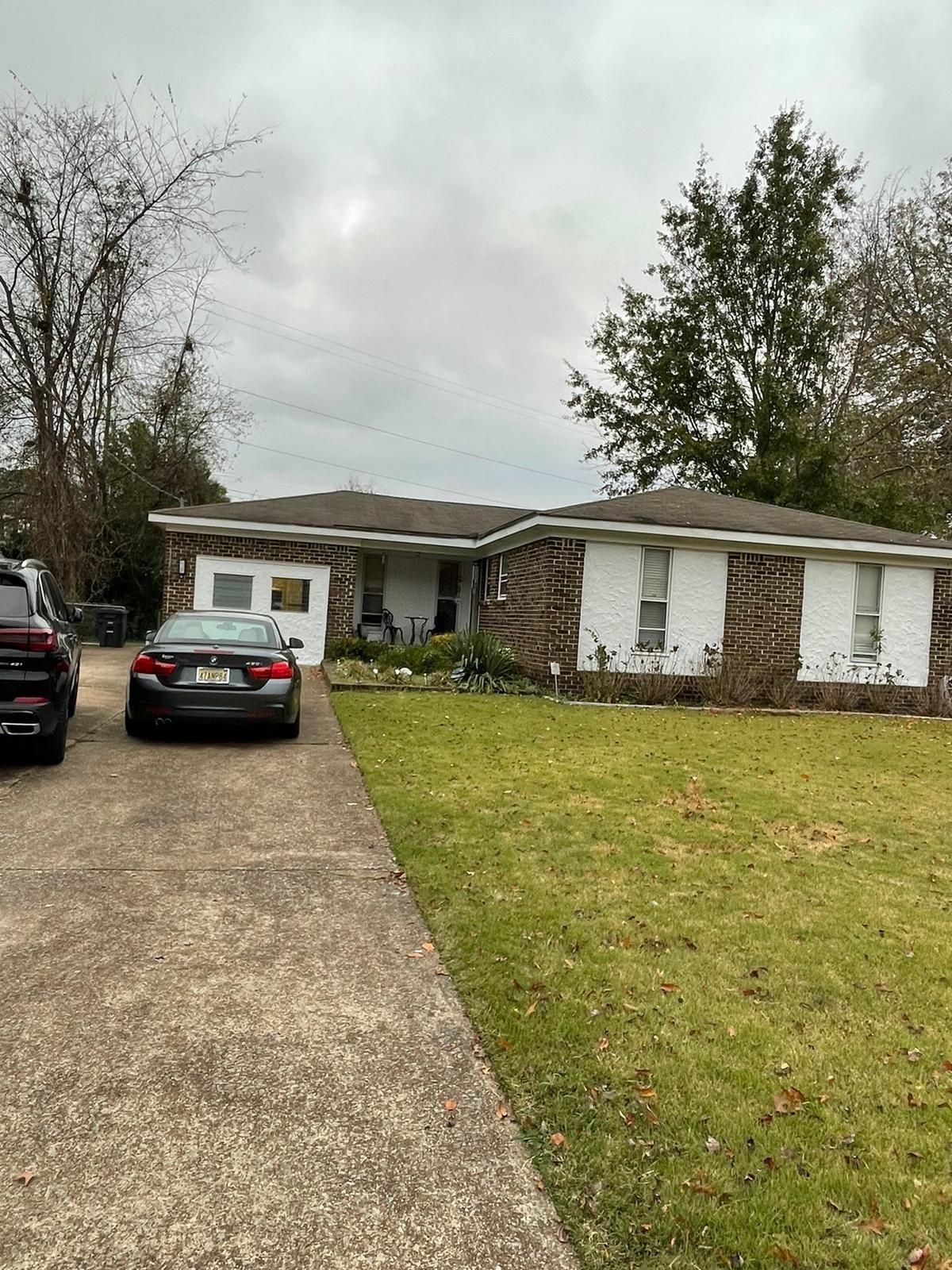 A car is parked in front of a house on a cloudy day.