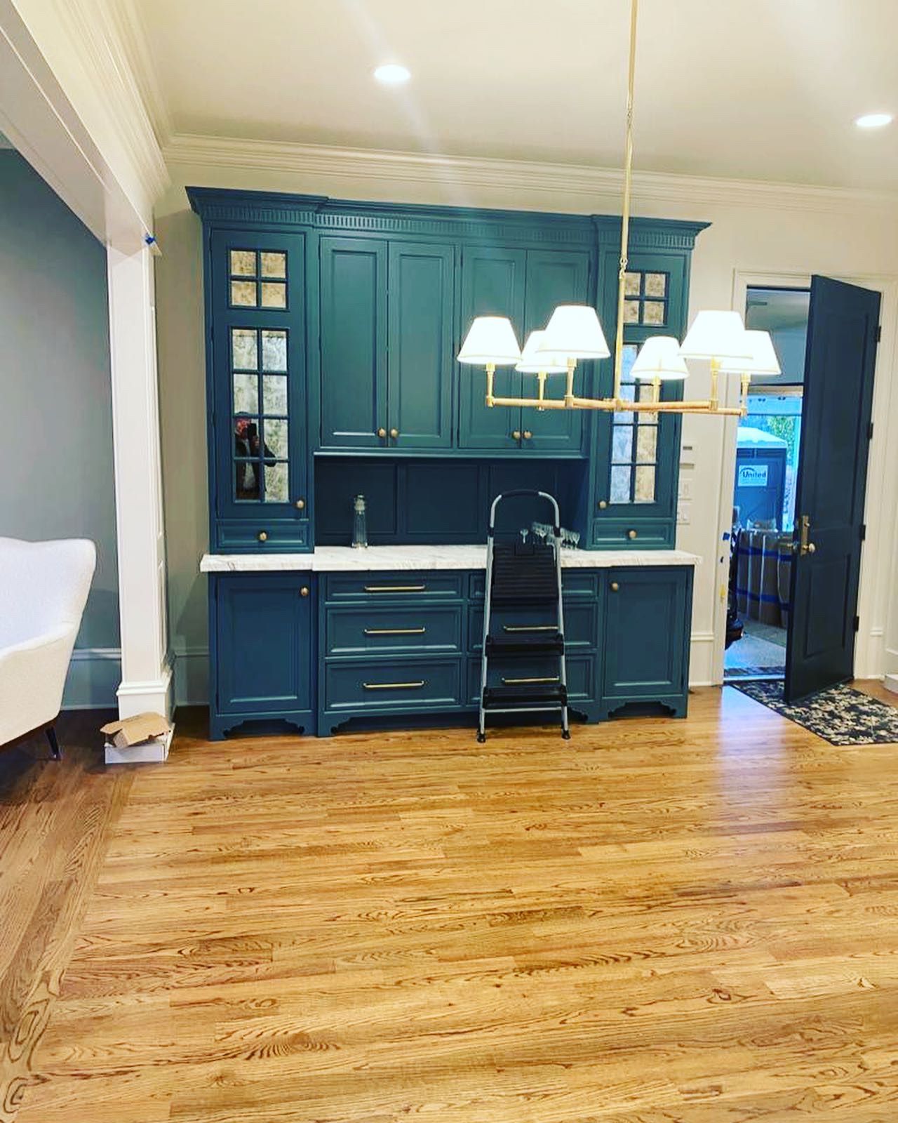 A kitchen with blue cabinets , hardwood floors and a chandelier.