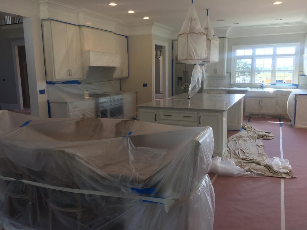 A kitchen that is being painted and covered in plastic