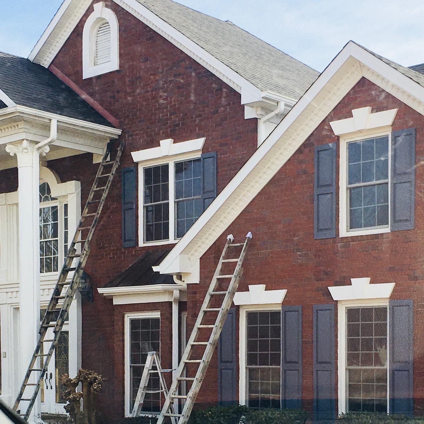 A red brick house with a white trim and blue shutters