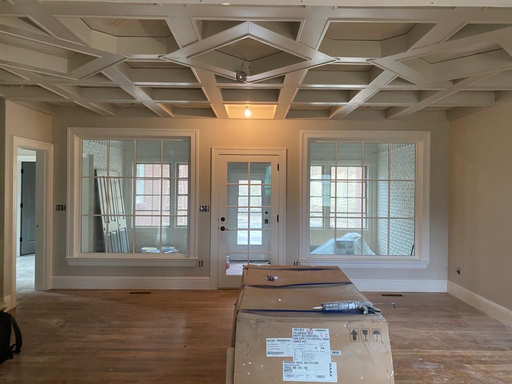 A living room with a lot of windows and a box on the floor.