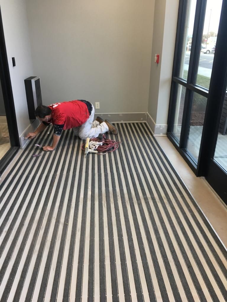 A man is kneeling on a striped carpet in a room.
