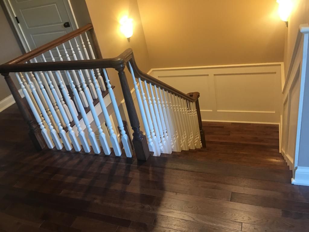 A staircase with a wooden railing and hardwood floors in a house.