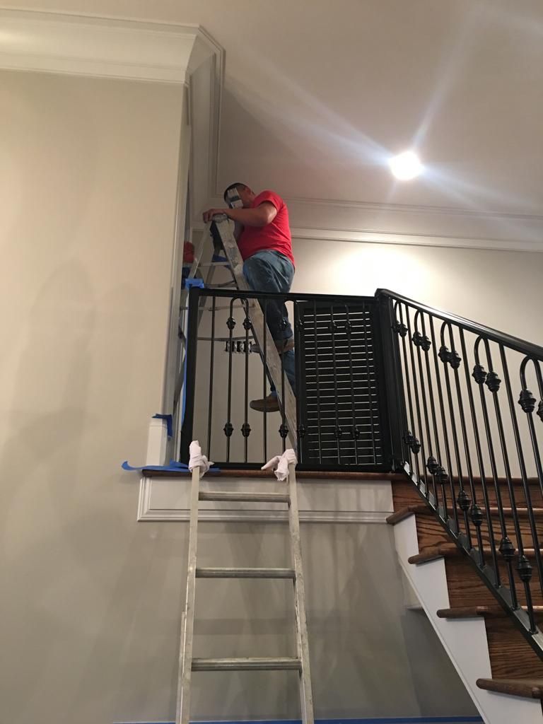 A man is standing on a ladder painting a wall.
