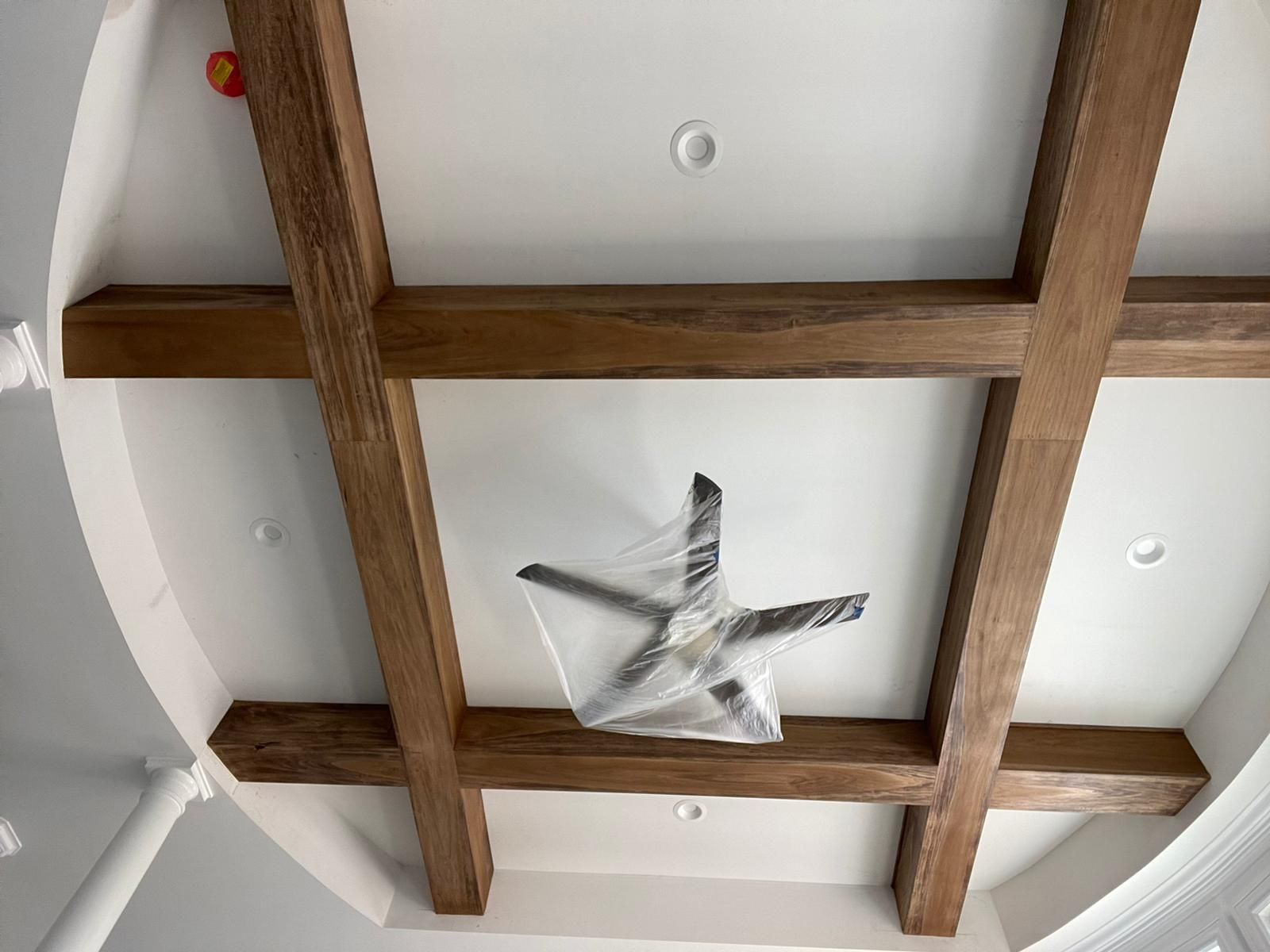 A ceiling fan is hanging from the ceiling of a room with wooden beams.