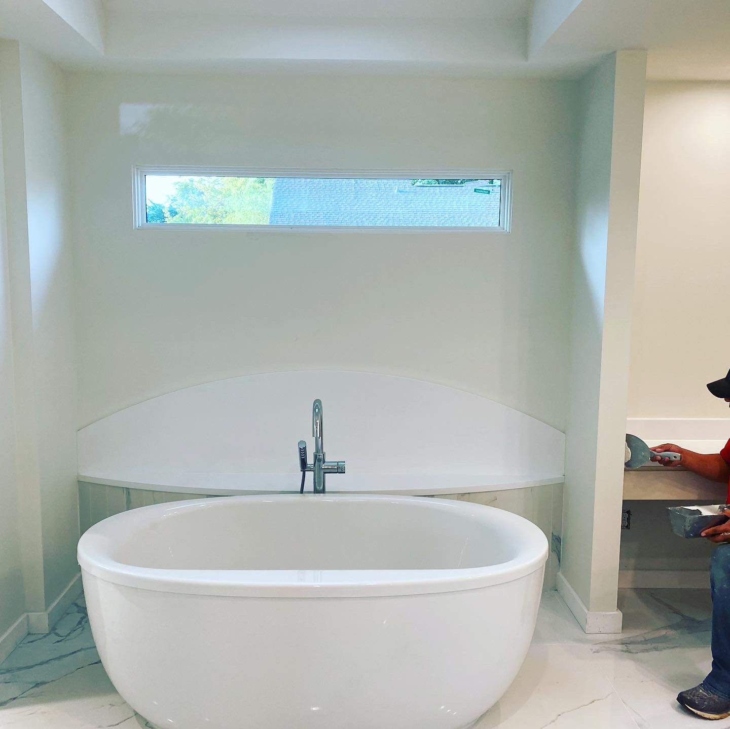 A person is sitting in a bathroom next to a bathtub