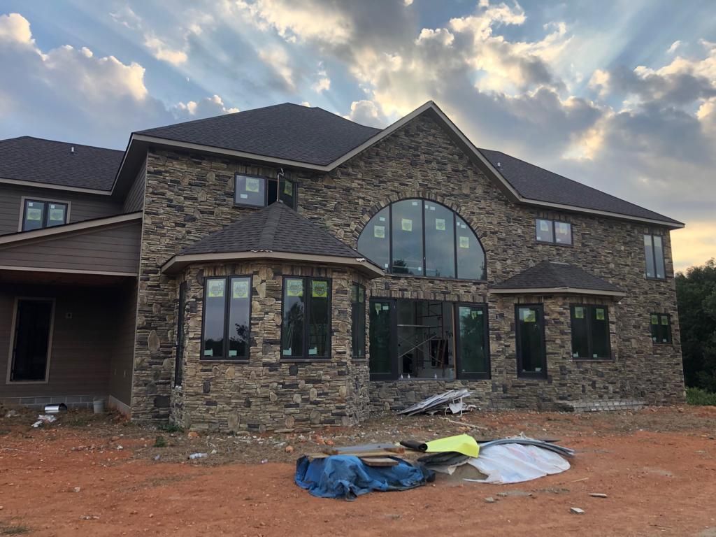 A large stone house with a lot of windows is being built.