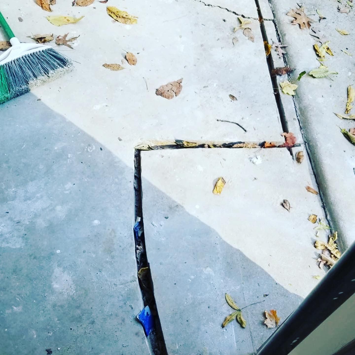 A green broom is sitting on a concrete surface