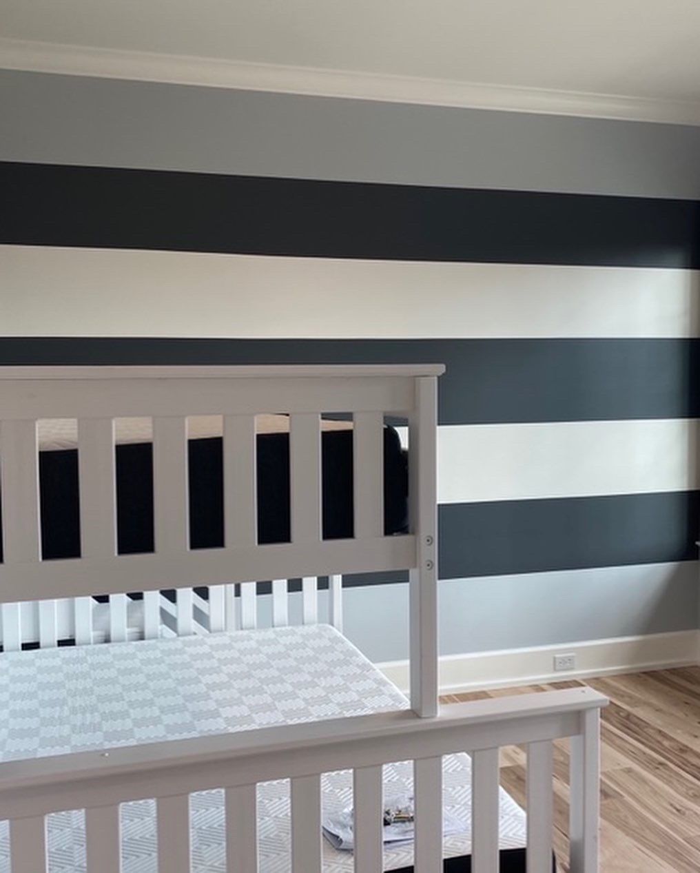 A bedroom with striped walls and a white bed