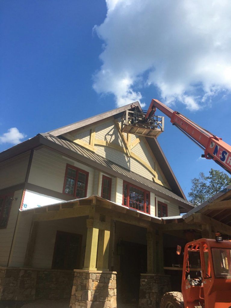 Worker on Lift Bucket Painting the Exterior of a Shop