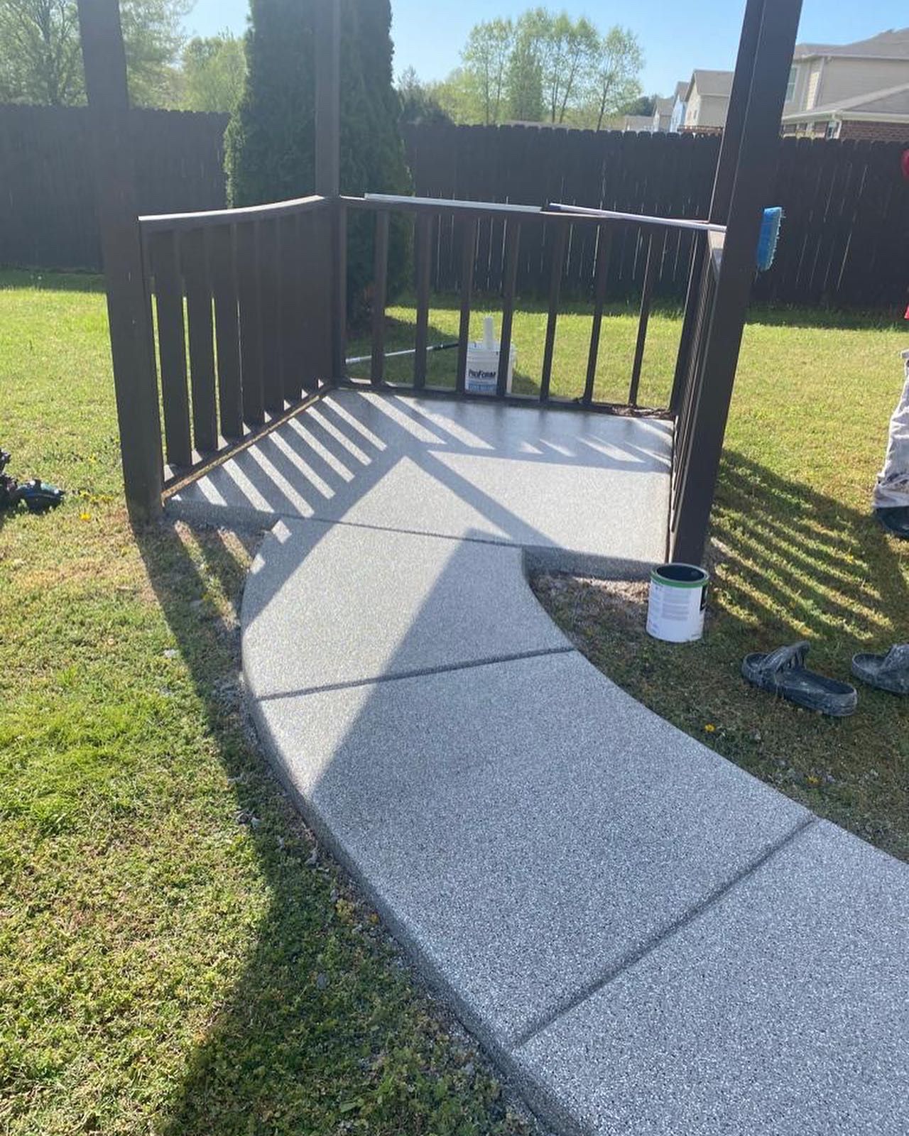 A concrete walkway leading to a deck in a backyard