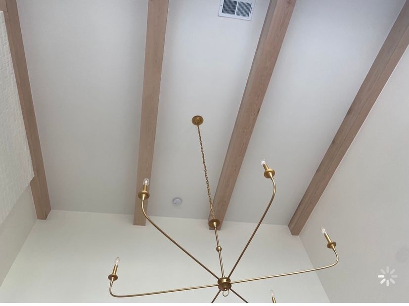 A ceiling with wooden beams and a chandelier hanging from it