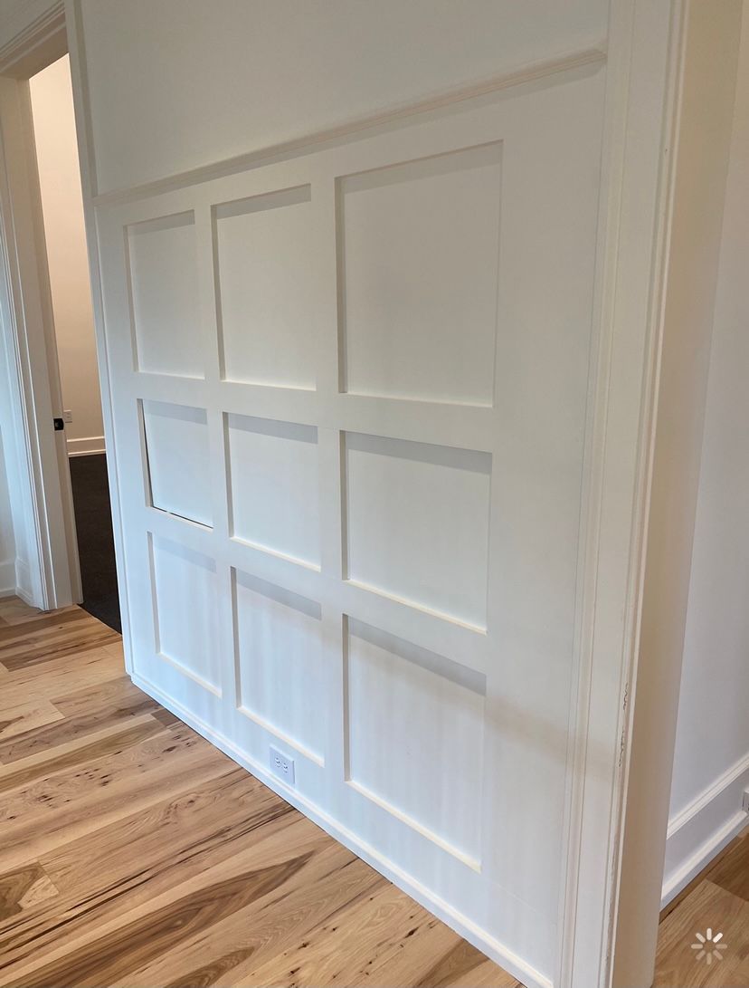 A white wall with wooden floors in a hallway.