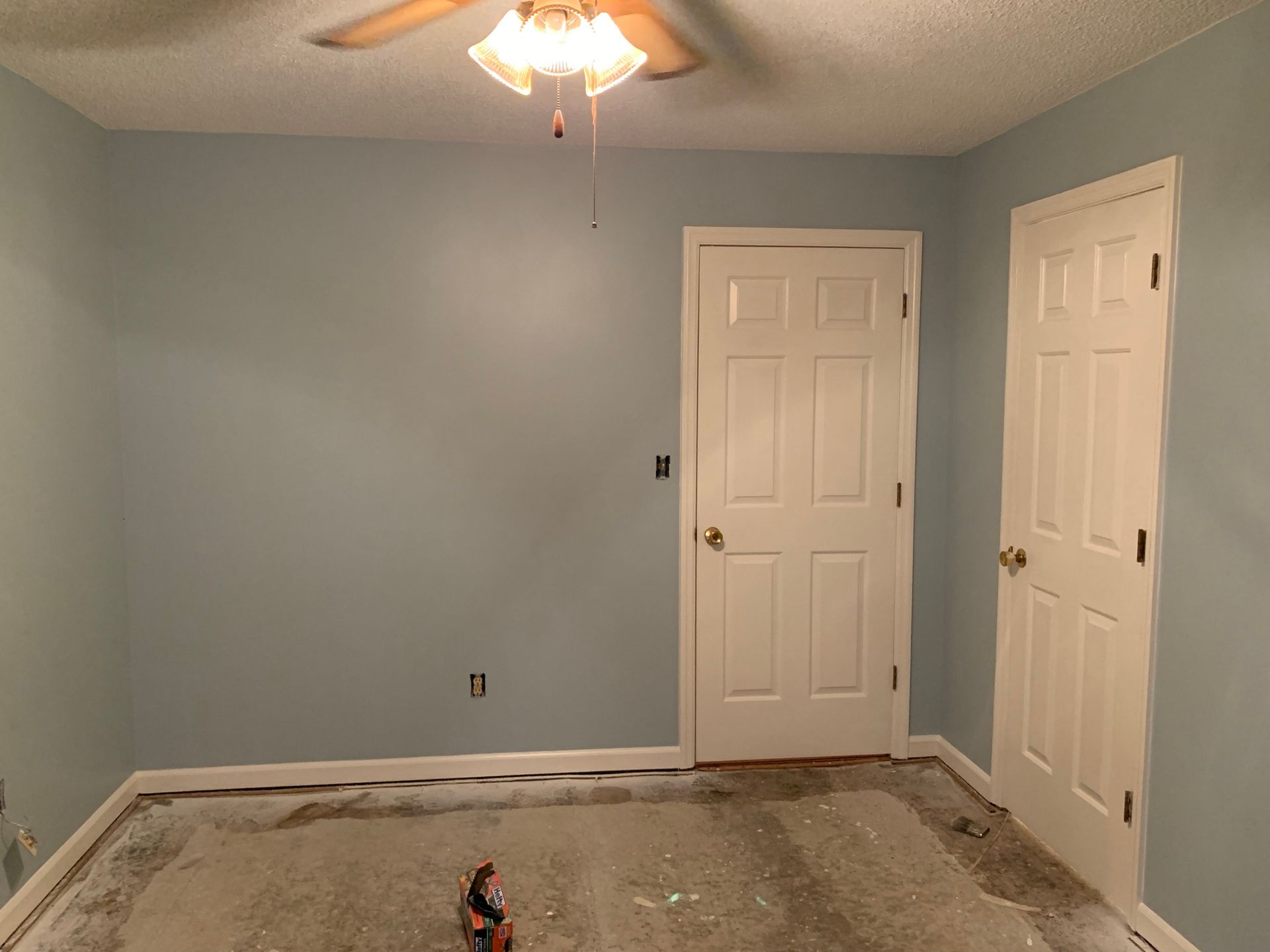 A room with blue walls and white doors and a ceiling fan