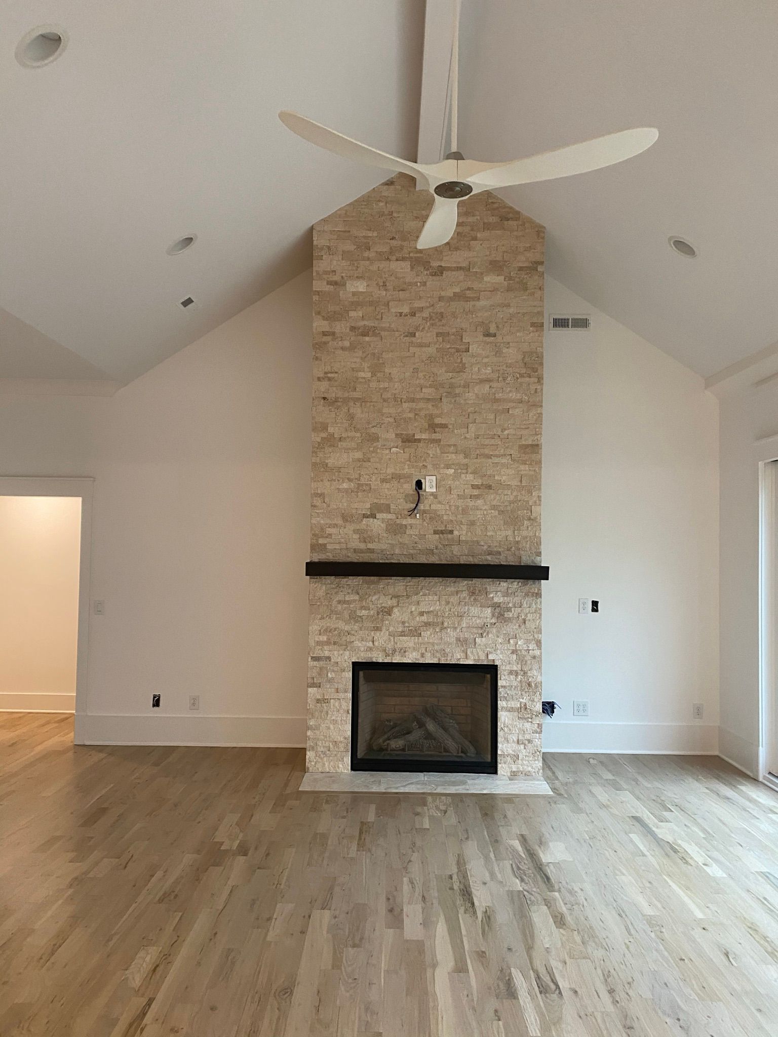An empty living room with a fireplace and a ceiling fan.