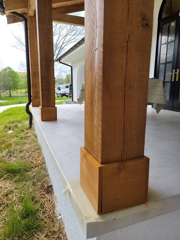 A wooden pillar on a porch next to a house.