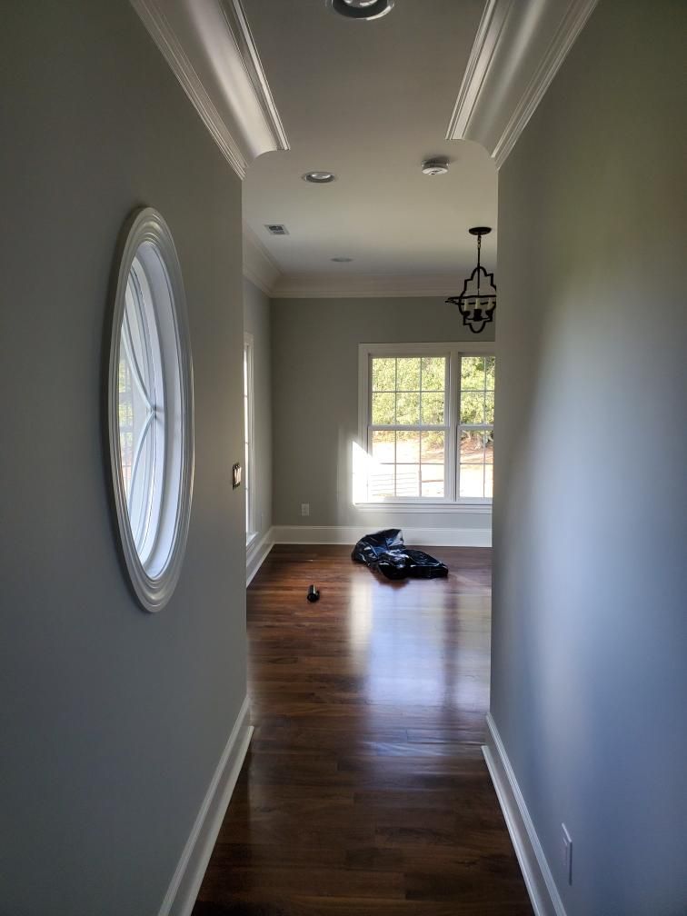 A hallway with a round window and a clock on the wall.