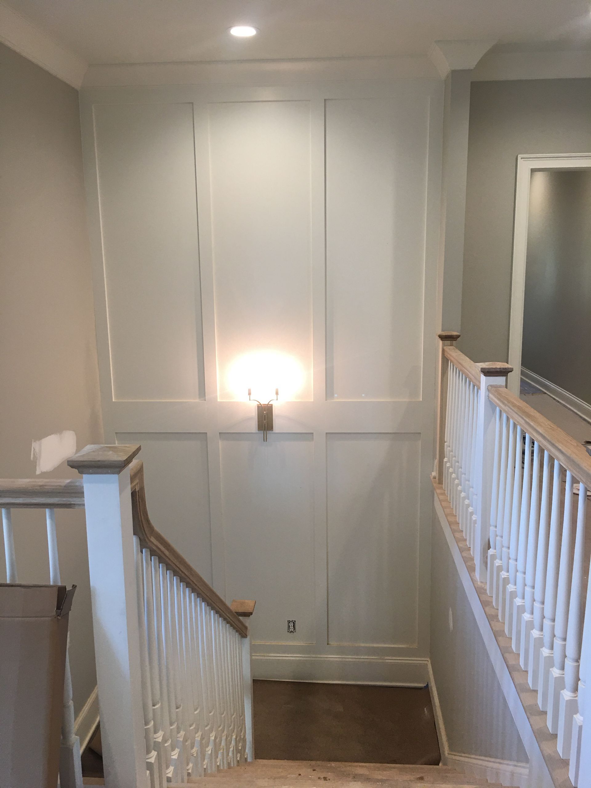 A staircase with a white railing and a lamp on the wall